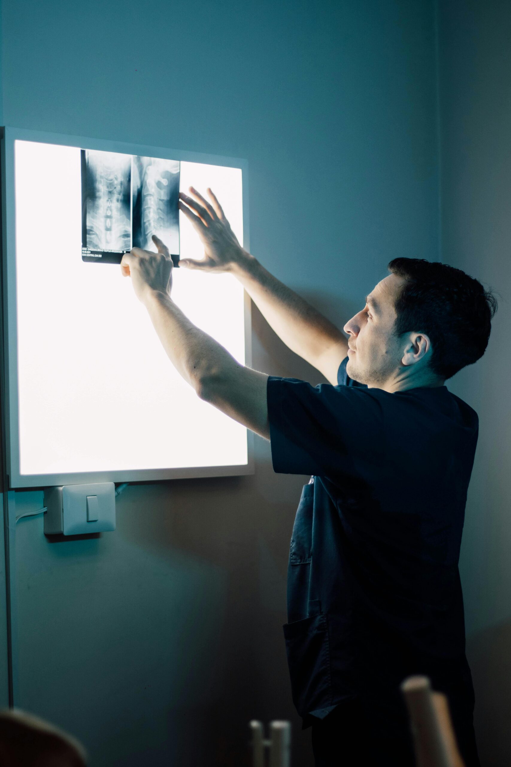 A healthcare worker studying an X-ray image on a lightbox in a clinic.